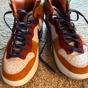 Women’s burnt orange, purple, cream dunks with green accents.